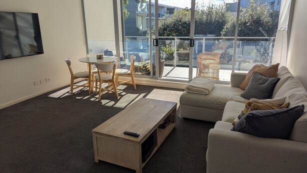Een moderne woonkamer met een bank, salontafel en eettafel.