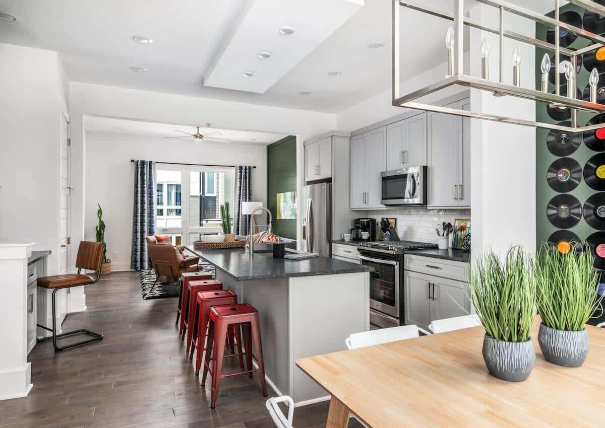 A modern kitchen with a central island, stainless steel appliances, and a vinyl record wall.