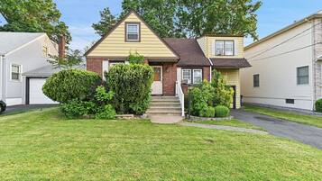 A two-story house with a front yard, a chimney, and a small front porch.