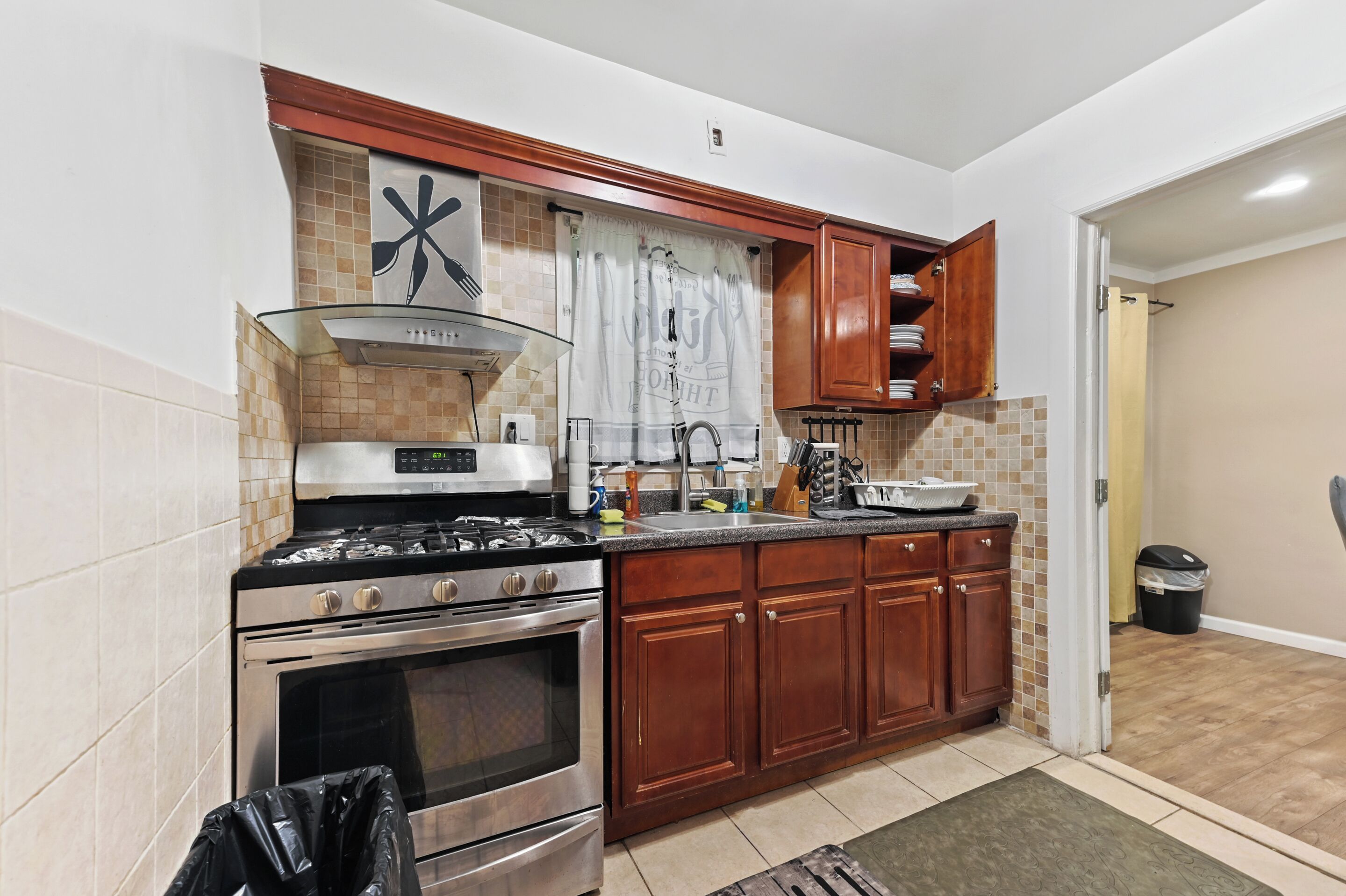 A compact kitchen with a gas stove, oven, and wooden cabinets.
