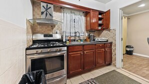 Cocina compacta con estufa a gas, horno y armarios de madera.