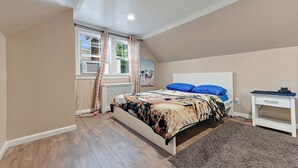 Un dormitorio con cama, mesita de noche, ventana con cortinas y radiador.
