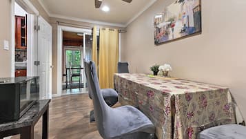 A dining area with a table covered in a floral tablecloth, two grey upholstered chairs, and a ceiling fan above.