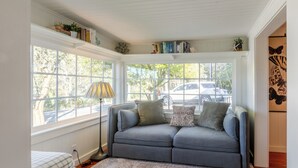 A cozy room with a gray sofa, a patterned rug, and a bookshelf filled with books and decorative items.