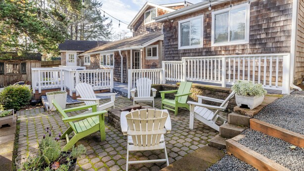 A patio area with outdoor furniture, a wooden deck, and a house with a shingled exterior.