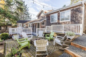 Een terras met buitenmeubilair, een houten terras en een huis met een gevel van houten schingles.