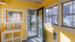 A room with yellow walls, a white door, and a window with a view of a wooden deck and outdoor furniture.