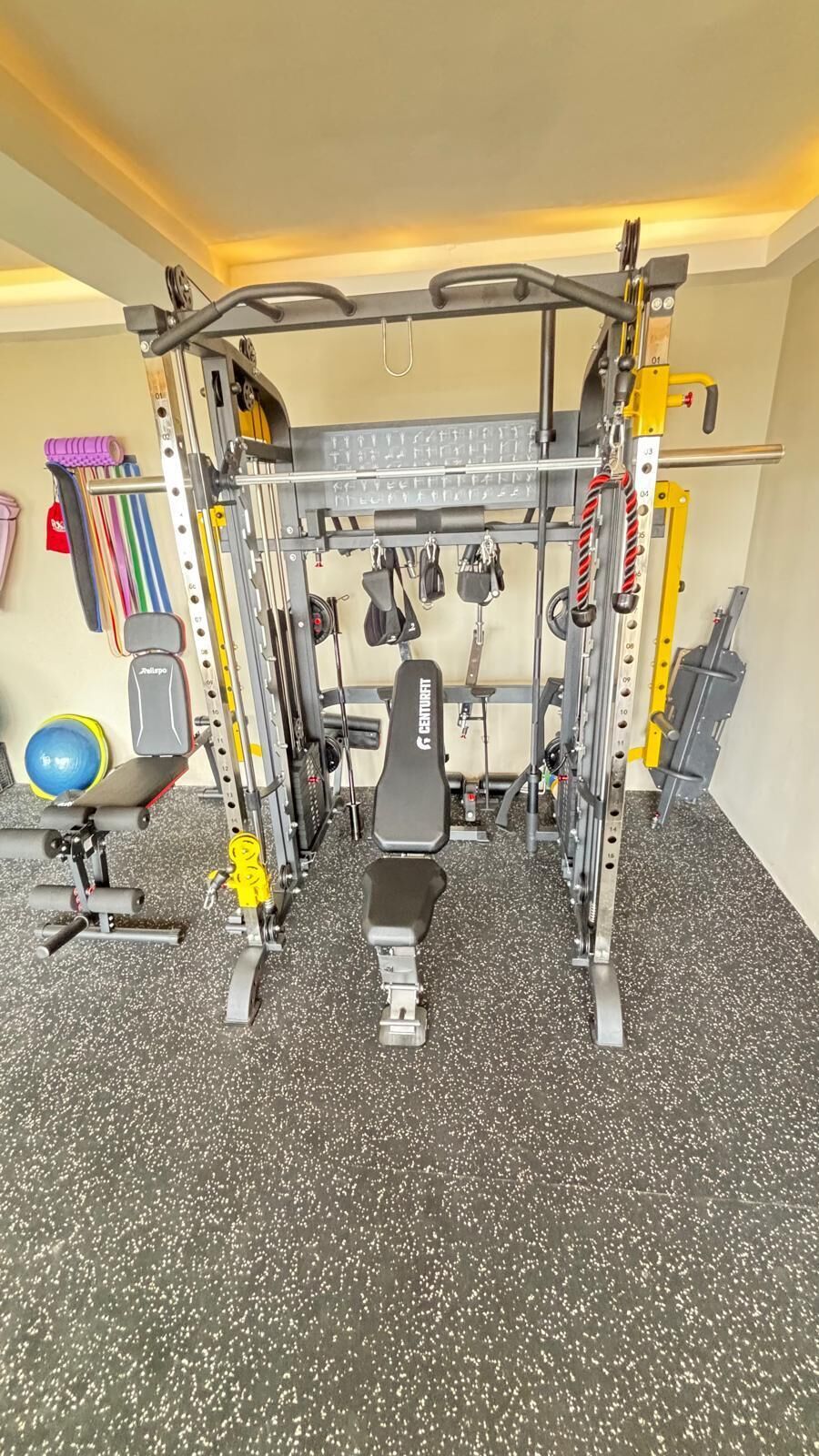 A gym with a bench press, weight racks, and various exercise equipment.