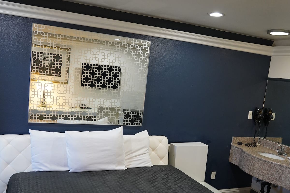 Ein Hotelzimmer mit einem großen Bett, einem weißen Sofa, einem Badezimmer mit Granitplatte und einer dekorativen Wandverkleidung.