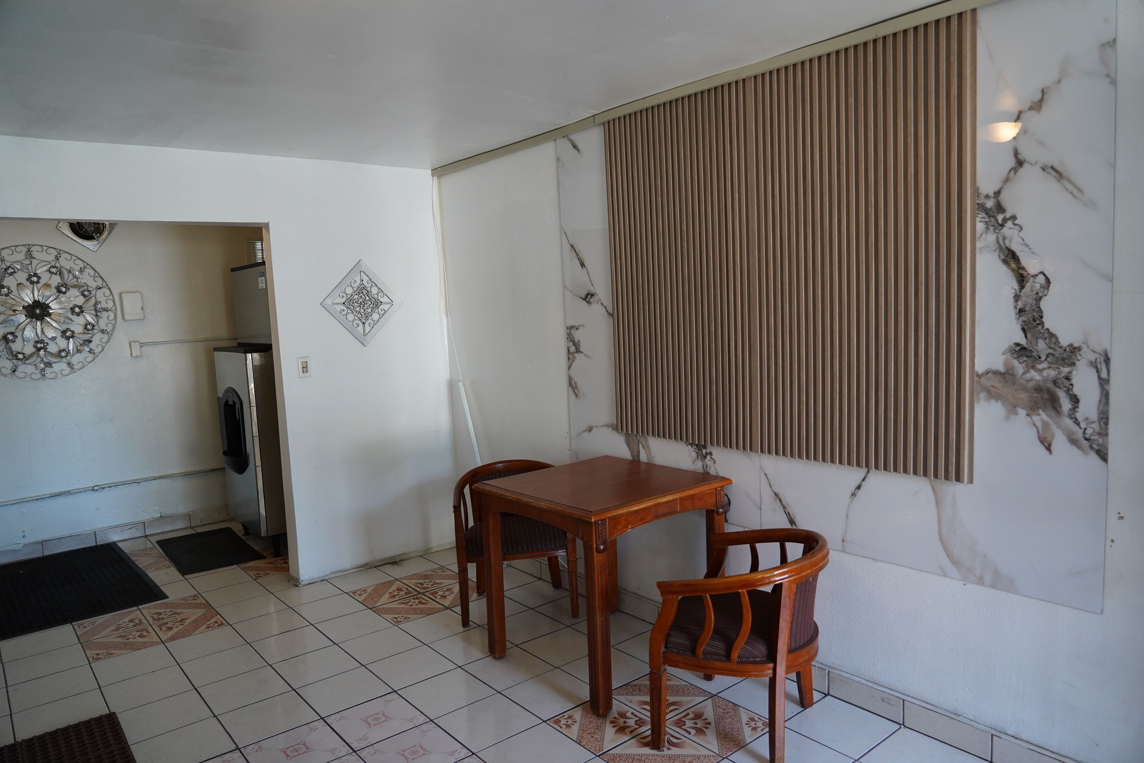 A dining area with a marble wall, a wooden table, and two chairs.
