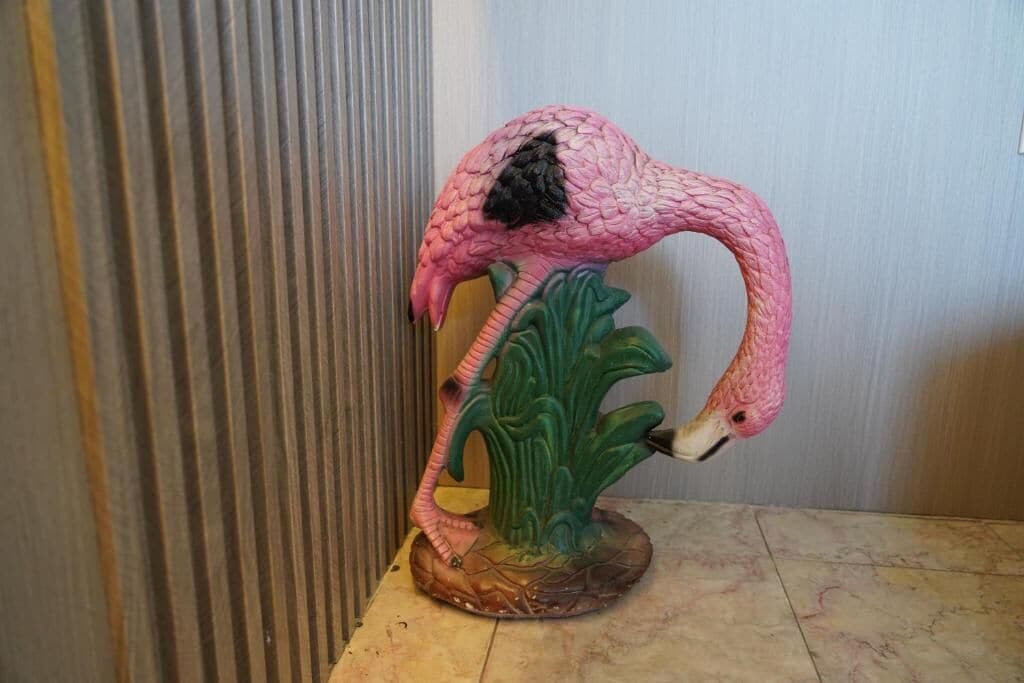 A pink flamingo sculpture on a wooden base.