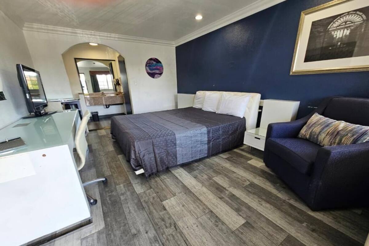 Ein Hotelzimmer mit Bett, Schreibtisch, Stuhl, Sofa und Fernseher.