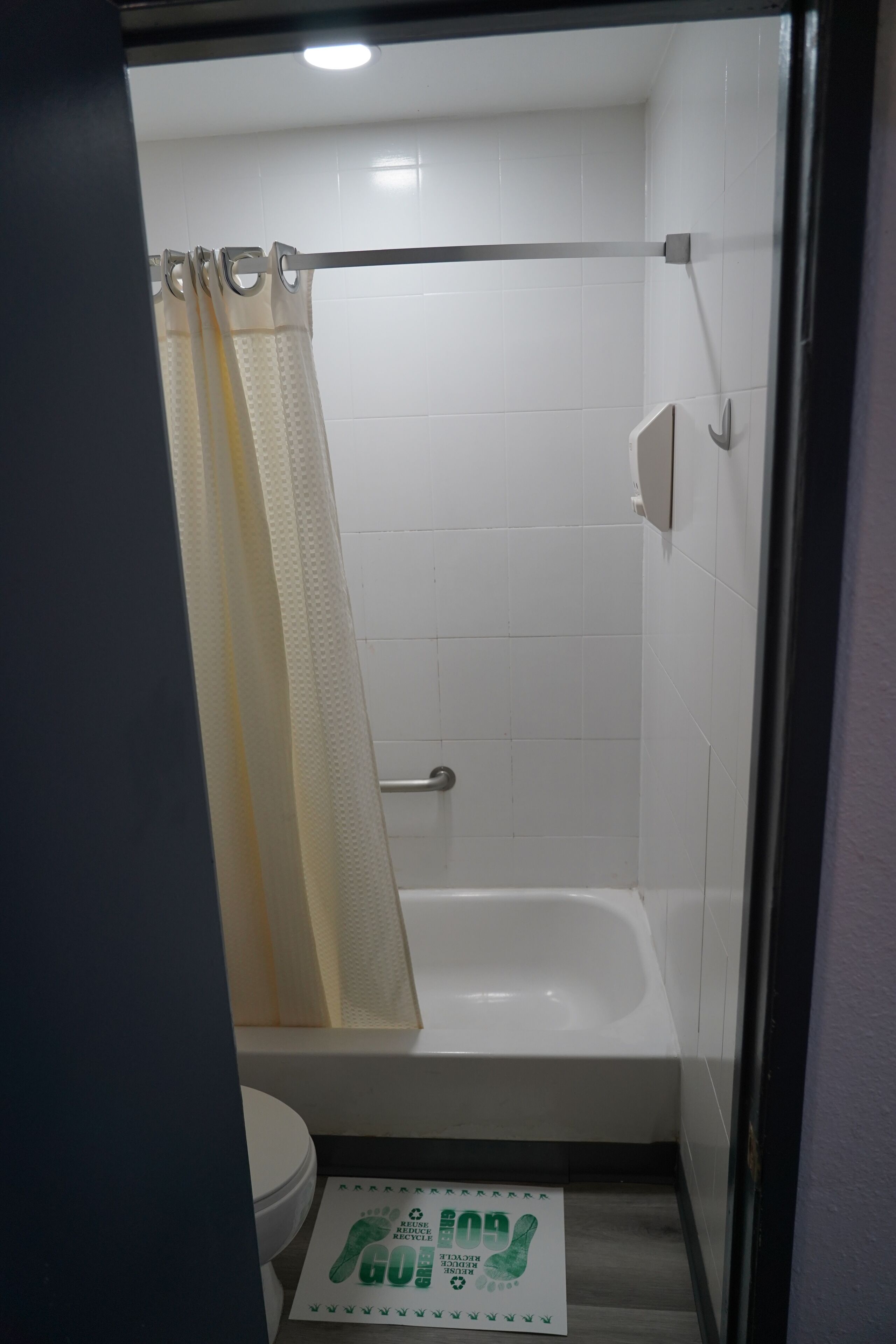 A small, enclosed bathroom with a white bathtub, a toilet, and a shower curtain.