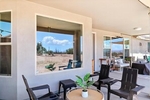 A modern outdoor seating area with a large window overlooking a desert landscape. - Charming 3BR Backyard Oasis+Family Friendly, sleeps 9 (Scottsdale)