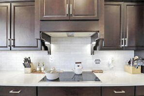 A modern kitchen with dark wood cabinets, a white tiled backsplash, and stainless steel appliances. - Charming 3BR Backyard Oasis+Family Friendly, sleeps 9 (Scottsdale)