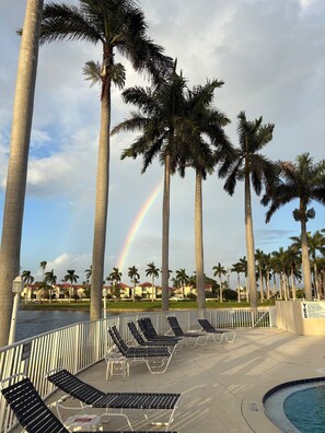 A poolside area with lounge chairs, palm trees, and a rainbow in the background. - A little slice of paradise in St Pete Beach (St. Petersburg)