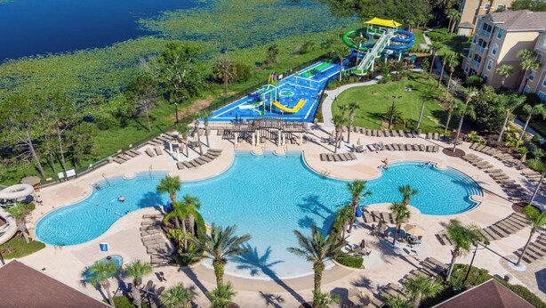 Um resort com uma piscina central ampla, parque aquático e área de praia.