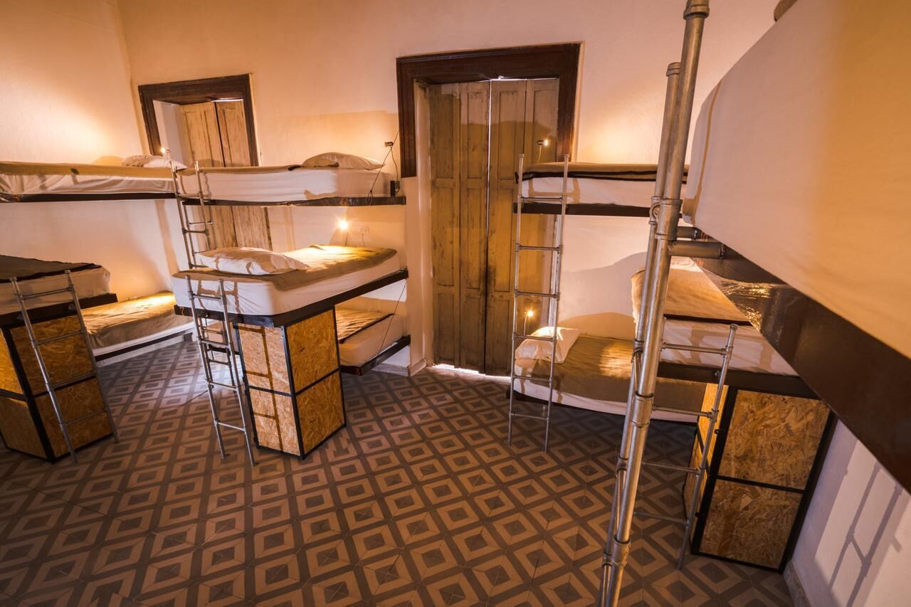 Une chambre de dortoir avec des lits superposés, une porte en bois et un sol à motifs.