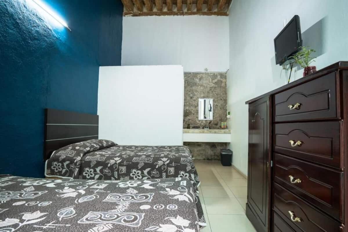 Ein Schlafzimmer mit Bett, Schminktisch, Fernseher und einer Steinwand.