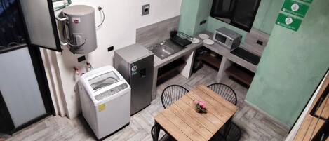 A compact kitchen with a dining area, a washing machine, and a small refrigerator.