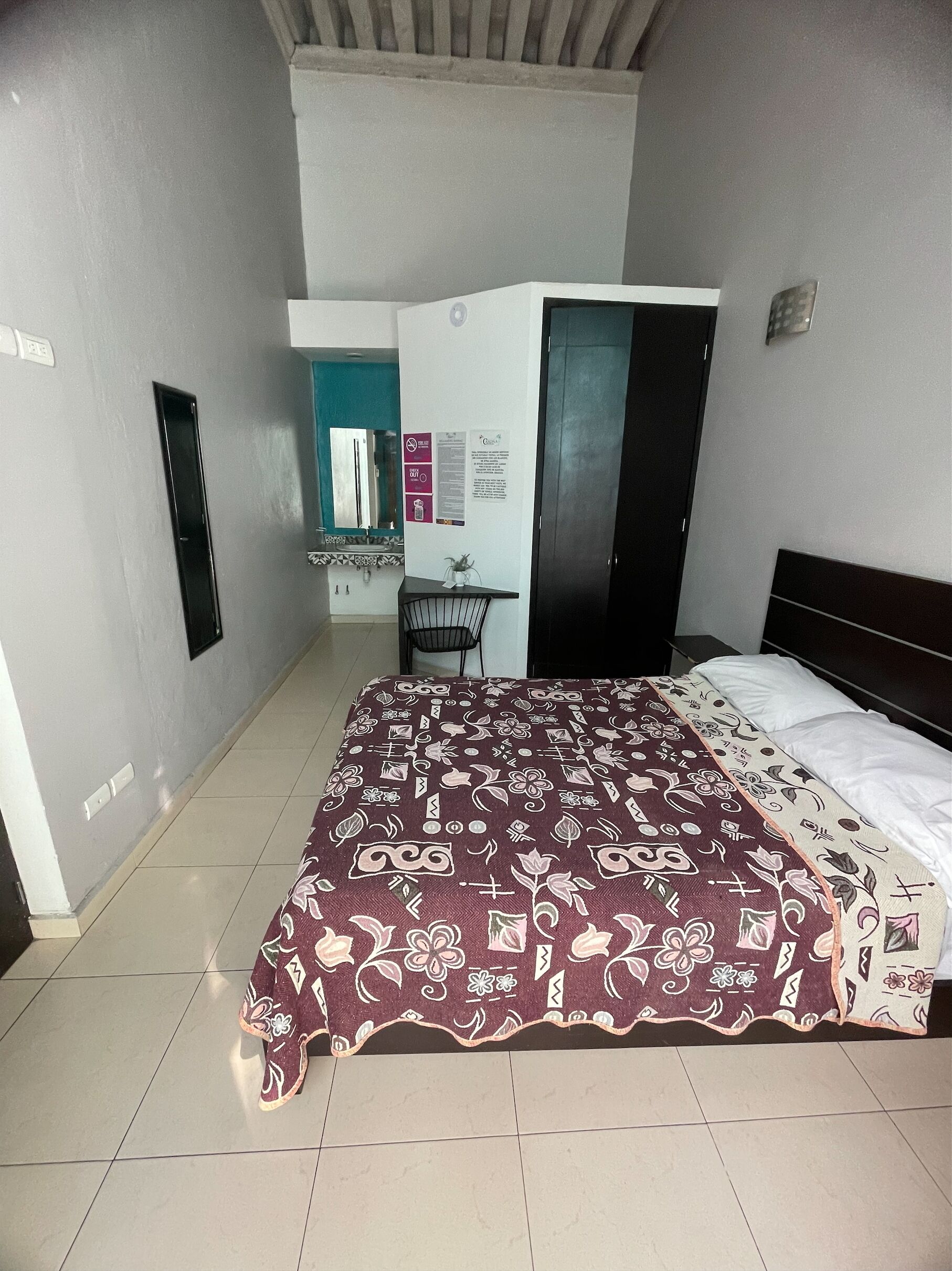 A bedroom with a bed, a desk, and a wardrobe.