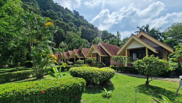 Un resort con diversi edifici in stile bungalow, immerso nel verde e circondato da un giardino curato.