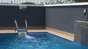 Ein Schwimmbecken mit Holzterrasse und Metallleitern.