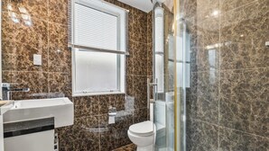 Ein Badezimmer mit Marmor-Spritzschutz, Toilette, Waschbecken und einer Duschkabine.