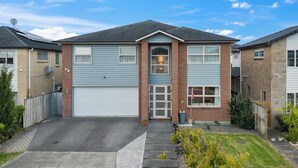 Ein zweigeschossiges Wohnhaus mit Garage, Veranda und kleinem Vorgarten.