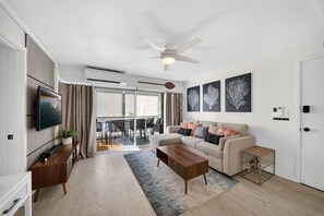 Ein modernes Wohnzimmer mit Sofa, Couchtisch, Fernseher und Kunstwerken.