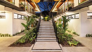 A modern staircase with a concrete pathway, surrounded by lush greenery and illuminated by large spherical lights. - Brand-New Casa Oso  Gated Luxury  Walk to Beach & Estuary Views (Tamarindo)