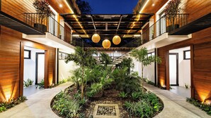 A modern building with a central courtyard, wooden balconies, and hanging spherical lights. - Brand-New Casa Oso  Gated Luxury  Walk to Beach & Estuary Views (Tamarindo)