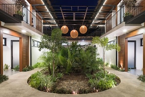 Ein modernes Interieur mit einem zentralen Garten, einer Treppe und einem Balkon mit Geländern.
