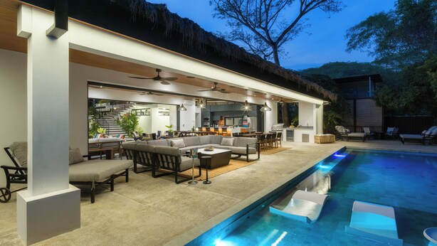 A modern outdoor living area with a pool, seating, and a kitchen area. - Brand-New Casa Oso  Gated Luxury  Walk to Beach & Estuary Views (Tamarindo)