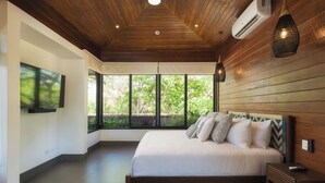 A modern bedroom with a large bed, wooden ceiling, and a TV on the wall. - Brand-New Casa Oso  Gated Luxury  Walk to Beach & Estuary Views (Tamarindo)