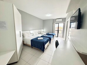 Quarto triplo conforto, sacada, vista parcial para o mar | Escrivaninha, espaço de trabalho para notebook, Wi-Fi de cortesia