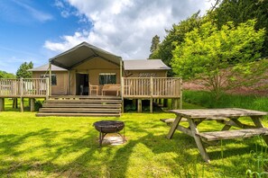 Un chalet rustique doté d’une terrasse, d’un barbecue et de tables de pique-nique.