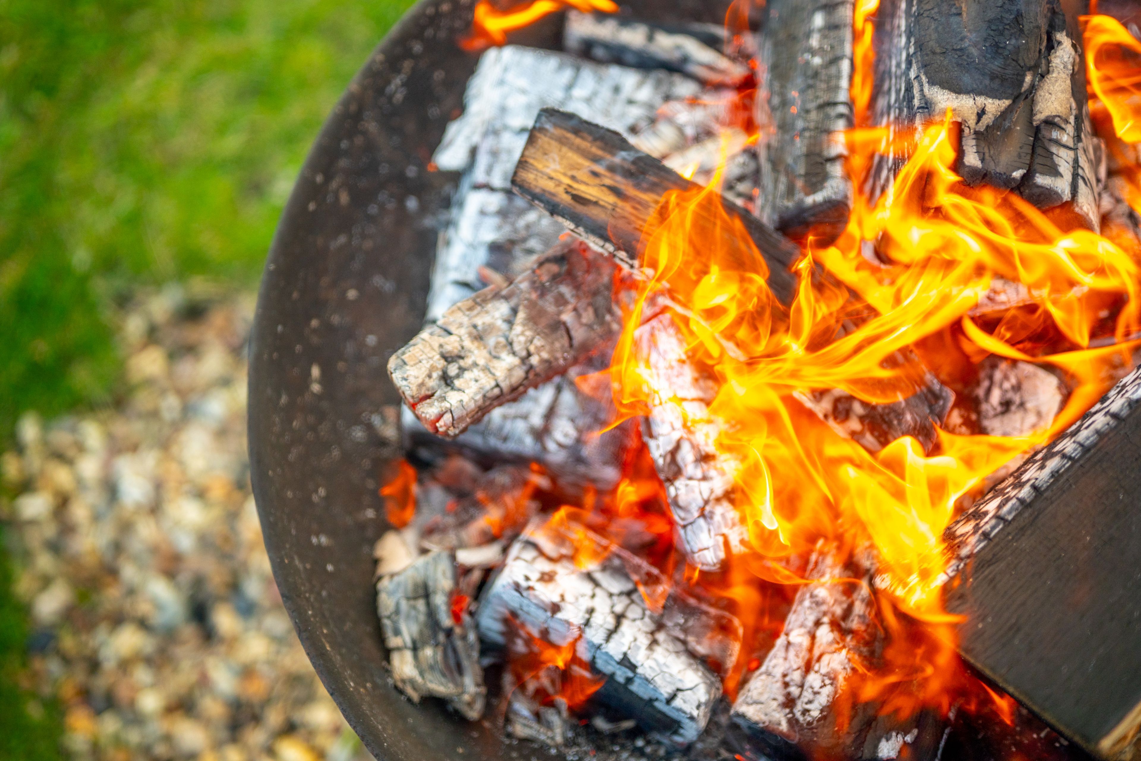 Un primo piano di un fuoco di campo con legno ardente e fiamme.