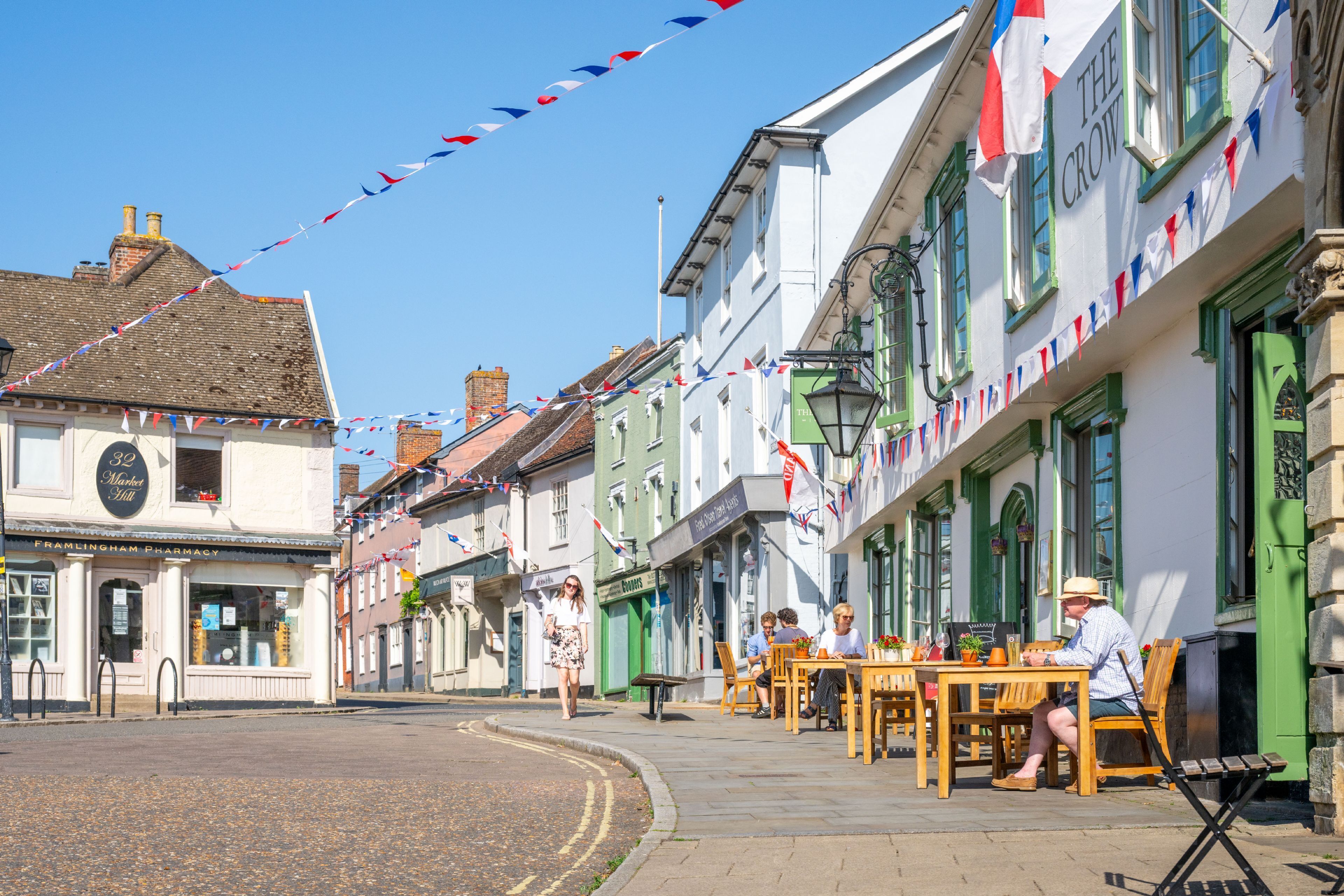 A street with buildings, outdoor seating, and a clear sky.