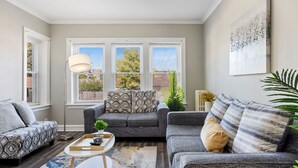 A modern living room with a grey sofa set, a round coffee table with a tray, and a floor lamp. - Serene Suburban Stay: Family-Friendly w/EZ Parking (Berwyn)