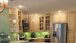 Una cocina con armarios de madera, un refrigerador de acero inoxidable, horno empotrado y una zona con taburete de bar.