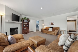 A spacious living room with a fireplace, leather sofas, a television, and a bookshelf. - Views for MILES ~ Remote Home in the Ranch (Butte)