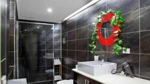 Ein modernes Badezimmer mit einem großen Spiegel, einem weißen Waschbecken und einer Duschkabine.
