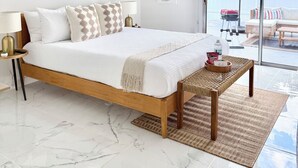 Une chambre à coucher moderne, dotée d’un grand lit, d’une table de chevet, d’une lampe et offrant une vue sur l’extérieur.
