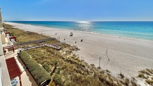 A beach with a clear sky, a pathway leading to the water, and a building with a red roof. - Beachfront Studio w/ Bunks Sleeps 4 at Majestic! (Panama City Beach)