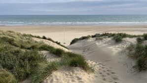 En strand med klitter og et flagstang i midten.