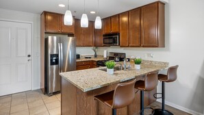 A modern kitchen with granite countertops, stainless steel appliances, wooden cabinets, and pendant lighting. - Chic Elevator Apt mins to DT, Train, Dining & Hosp (Berwyn)
