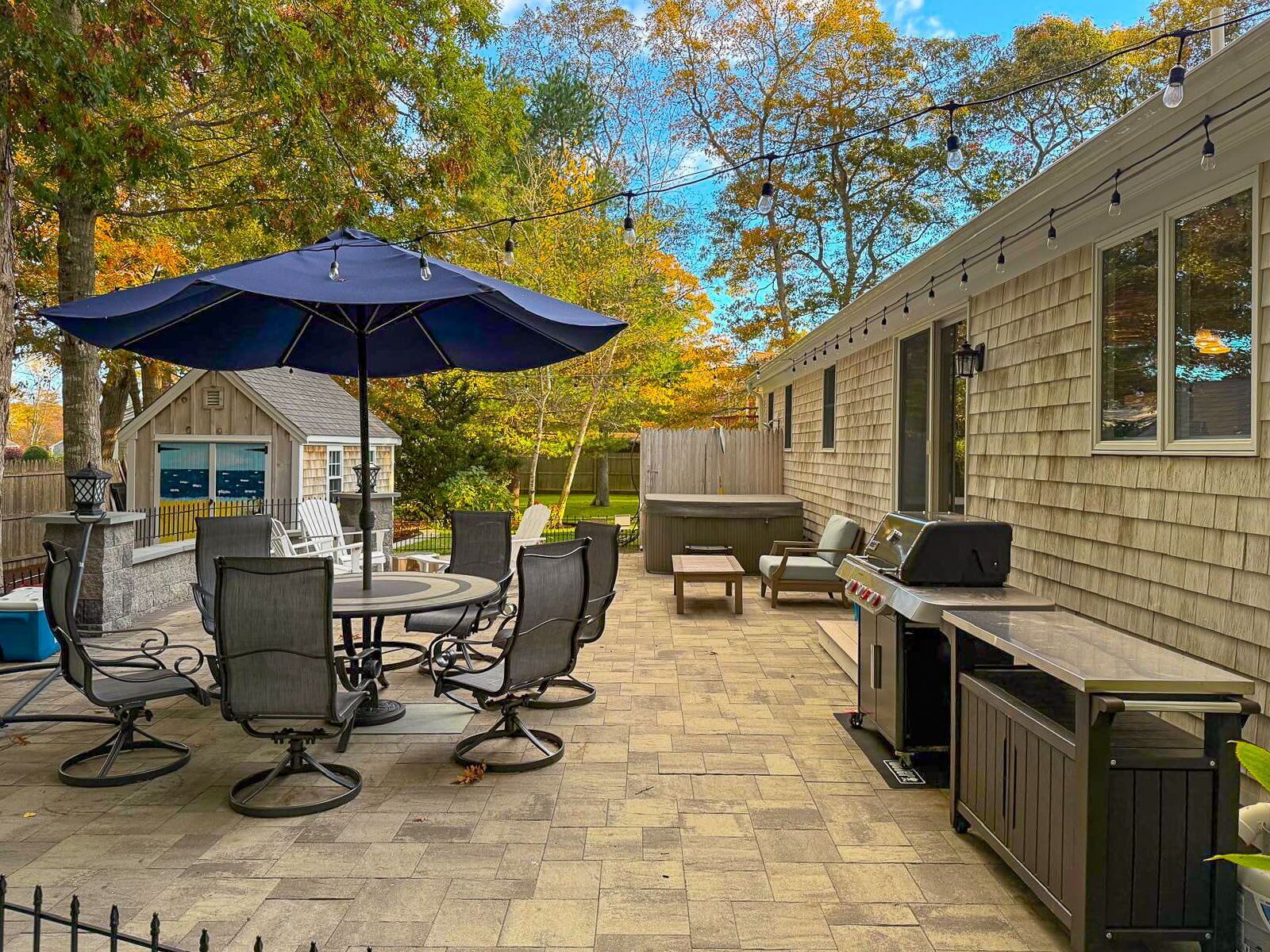 Een terras met tuinmeubilair, een barbecue en een jacuzzi.