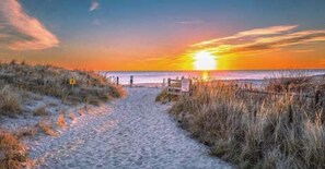 A beach path leading to the ocean with a sunset in the background. - Cape Cod Fireplace/ Hot Tub Fire Pit & Beach (Barnstable)