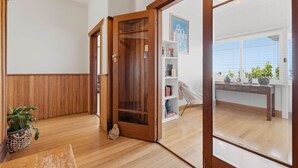 A wooden-floored hallway with a sliding glass door leading to a room with a view. - Poets View - 3 Bedroom House (West Hobart)